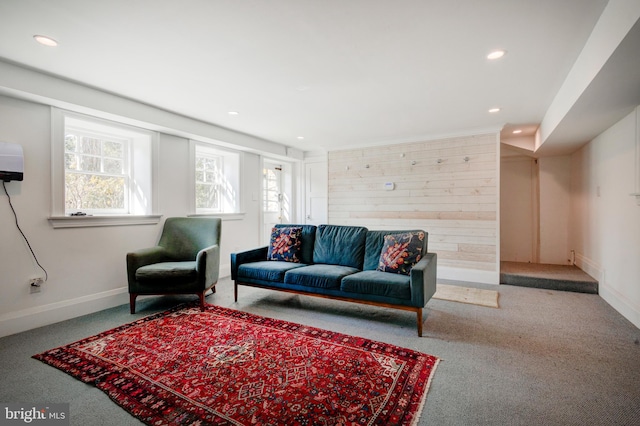 carpeted living room with wood walls