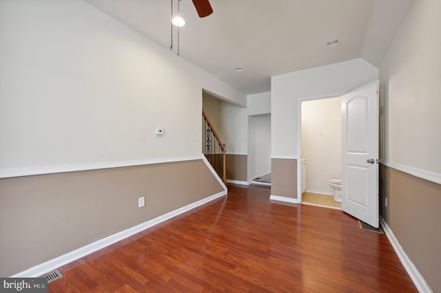 unfurnished bedroom featuring connected bathroom, ceiling fan, and dark wood-type flooring