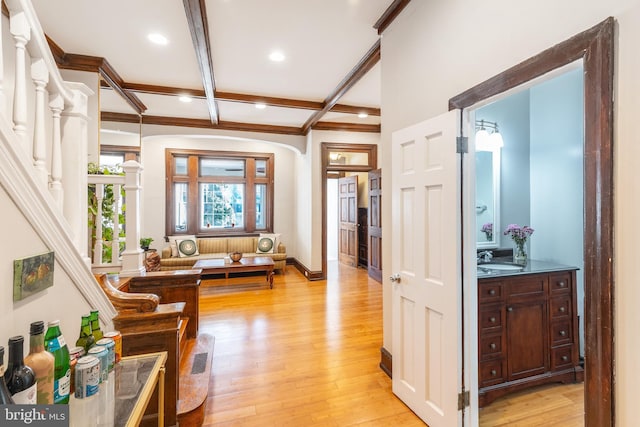 living room featuring coffered ceiling, beamed ceiling, light hardwood / wood-style flooring, and sink