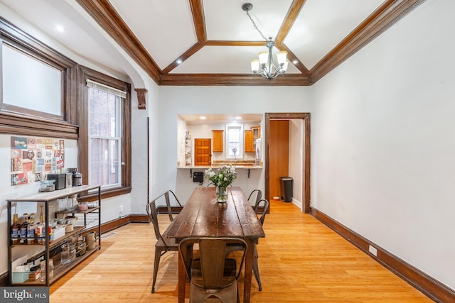 dining area featuring crown molding, an inviting chandelier, vaulted ceiling, and light wood-type flooring