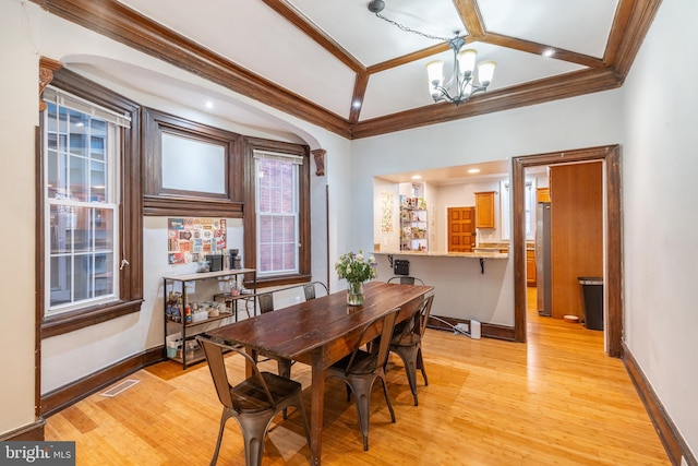 dining space with a notable chandelier, crown molding, and light hardwood / wood-style floors