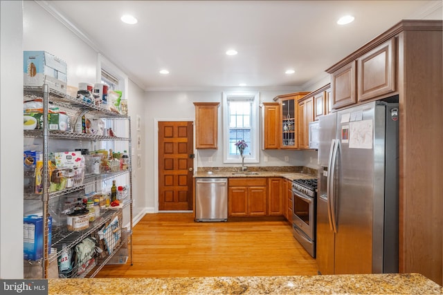 kitchen featuring appliances with stainless steel finishes, crown molding, light hardwood / wood-style floors, and light stone countertops