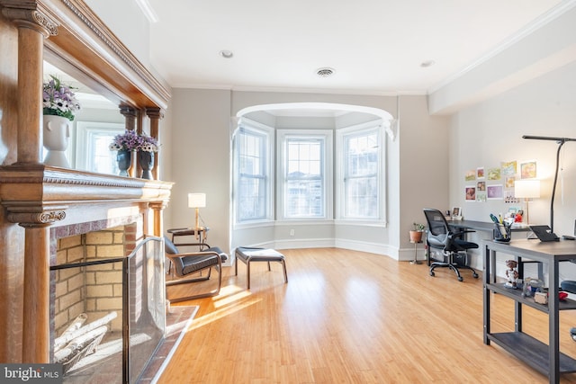 office area with light hardwood / wood-style floors, ornamental molding, and a fireplace