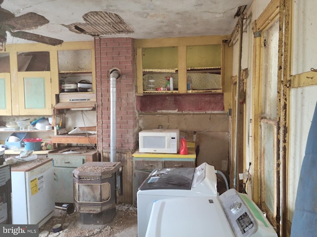 interior space featuring washer and dryer, brick wall, and a wood stove