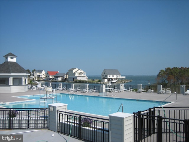 view of swimming pool featuring a water view and a patio