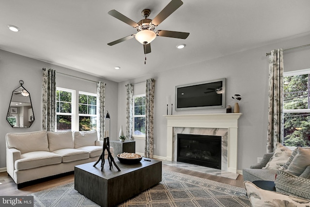 living room featuring hardwood / wood-style floors, ceiling fan, and a fireplace