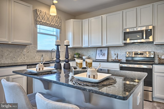 kitchen with white cabinets, appliances with stainless steel finishes, a kitchen breakfast bar, and pendant lighting