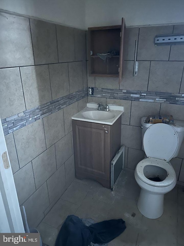 bathroom with toilet, tile walls, tile flooring, and vanity