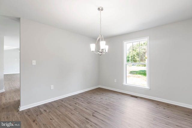 empty room with hardwood / wood-style floors and a notable chandelier