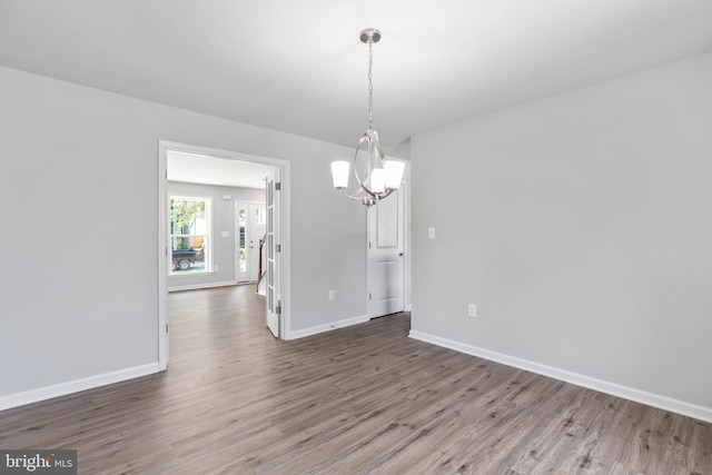 spare room featuring a chandelier and dark hardwood / wood-style floors