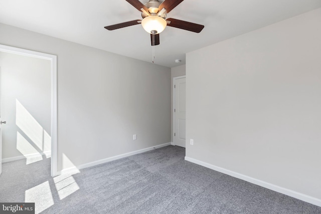 empty room featuring ceiling fan and dark carpet