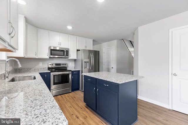 kitchen featuring white cabinets, light wood-type flooring, blue cabinets, and stainless steel appliances