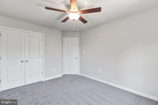 unfurnished bedroom featuring ceiling fan, dark carpet, and a closet