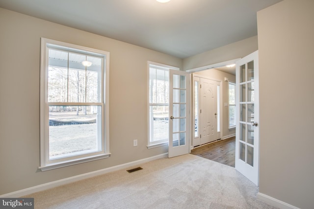 unfurnished room with light carpet and french doors