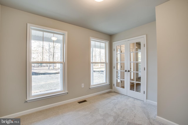 spare room featuring light colored carpet and french doors