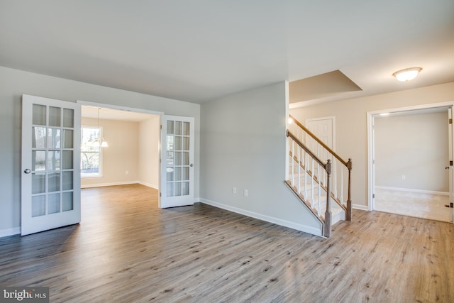 spare room with a chandelier, french doors, and light hardwood / wood-style flooring