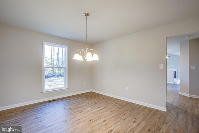 empty room with a notable chandelier and light wood-type flooring