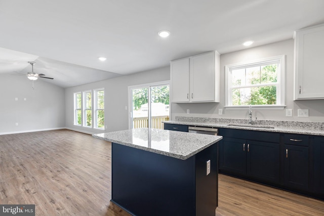 kitchen with light hardwood / wood-style floors, vaulted ceiling, ceiling fan, white cabinets, and sink