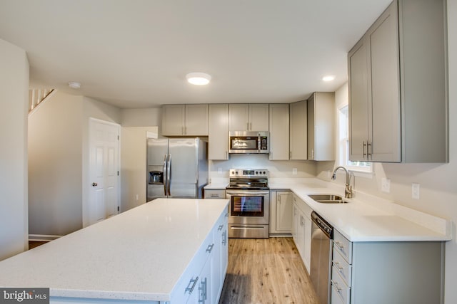 kitchen featuring light hardwood / wood-style floors, stainless steel appliances, a kitchen island, gray cabinets, and sink