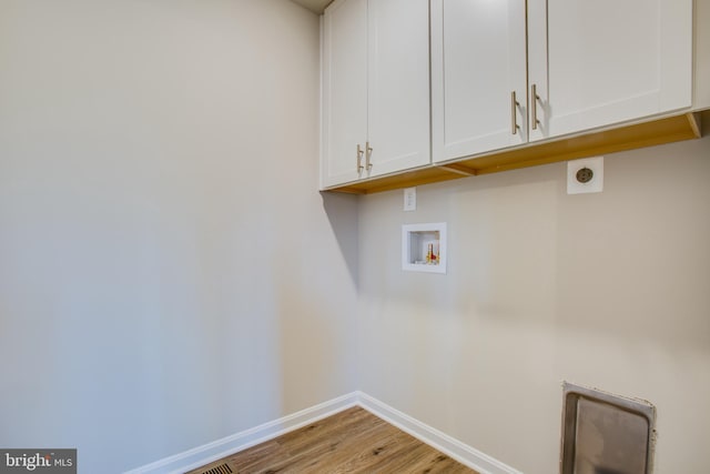 washroom featuring washer hookup, electric dryer hookup, light hardwood / wood-style flooring, and cabinets