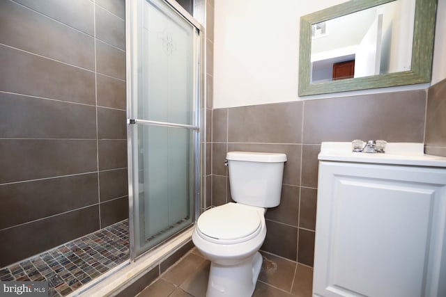 bathroom with tile walls, a shower with door, tile flooring, and vanity