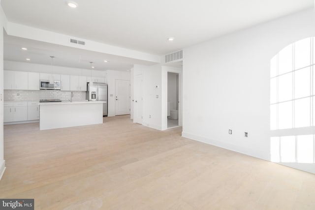 unfurnished living room featuring sink and light wood-type flooring