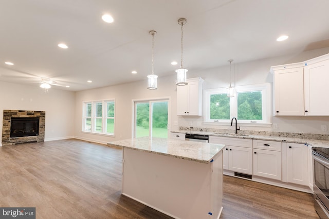 kitchen featuring light hardwood / wood-style floors, white cabinets, a kitchen island, pendant lighting, and a fireplace