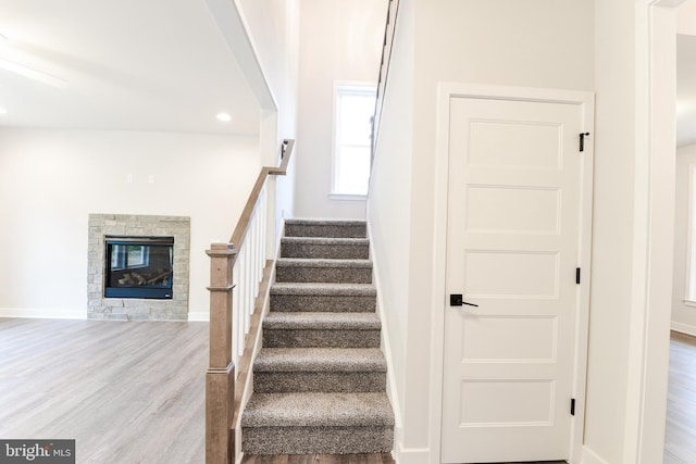 staircase featuring light hardwood / wood-style floors and a fireplace