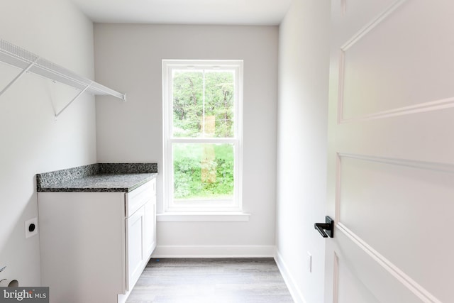 laundry area with cabinets, hookup for an electric dryer, and light wood-type flooring