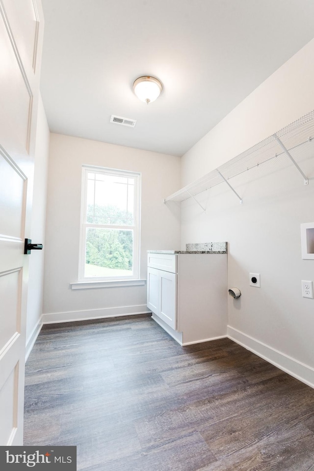 laundry room featuring cabinets, electric dryer hookup, and dark wood-type flooring