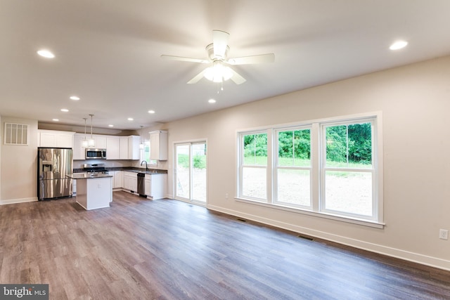 kitchen featuring stainless steel appliances, ceiling fan, hardwood / wood-style floors, white cabinets, and hanging light fixtures