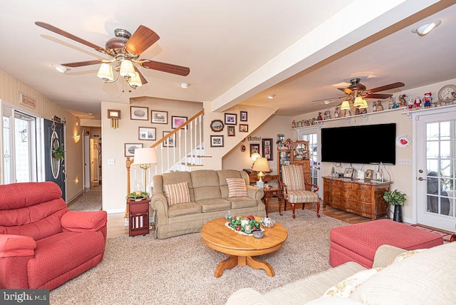 living room with beamed ceiling, ceiling fan, and light wood-type flooring