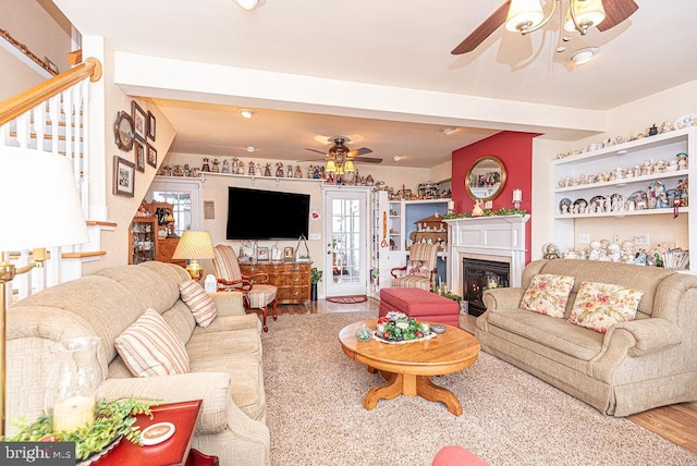 living room with beam ceiling, light hardwood / wood-style floors, and ceiling fan with notable chandelier