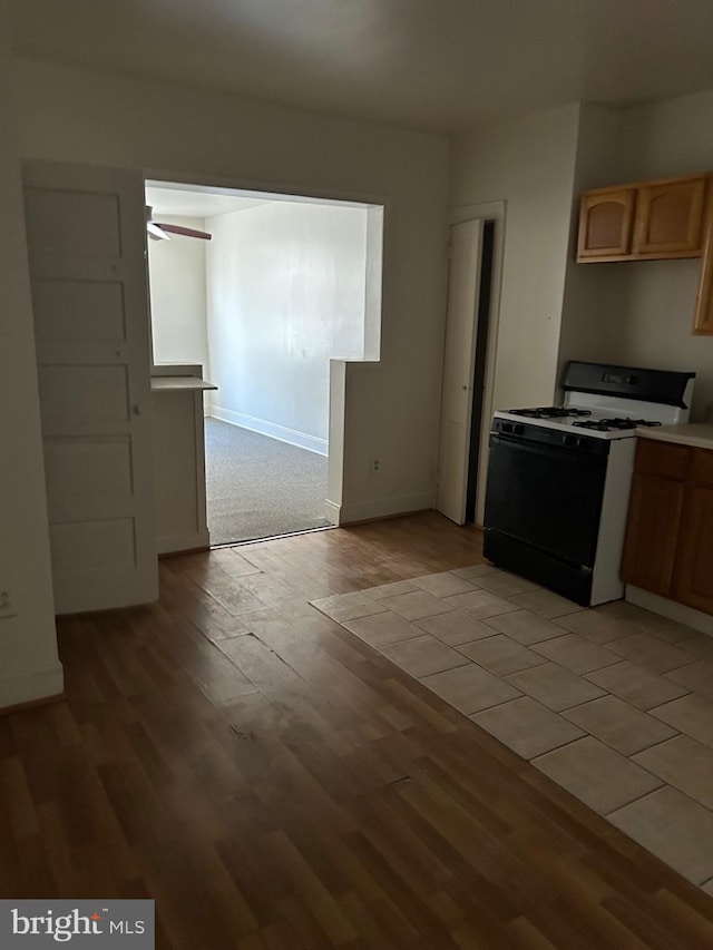 kitchen with ceiling fan, light brown cabinetry, light hardwood / wood-style floors, and gas range gas stove