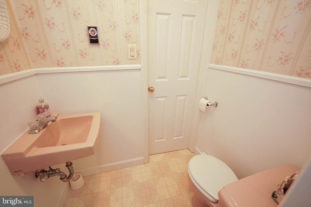 bathroom featuring toilet, tile flooring, and sink