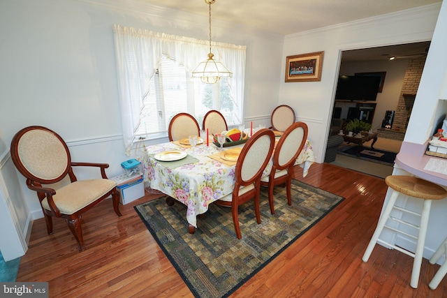 dining room featuring brick wall, crown molding, and hardwood / wood-style flooring