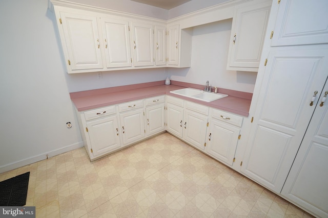 kitchen featuring sink, light tile floors, and white cabinetry