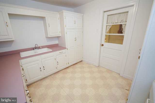 kitchen with sink, white cabinets, and light tile floors