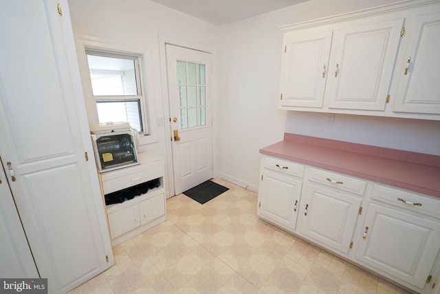 kitchen with light tile floors and white cabinetry