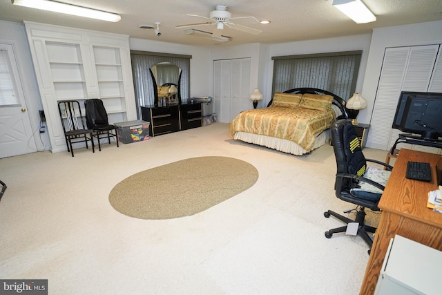 carpeted bedroom featuring ceiling fan and two closets