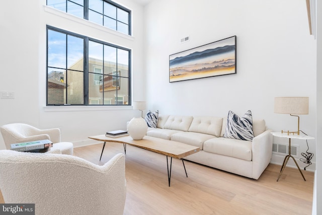 living room with a towering ceiling and wood-type flooring