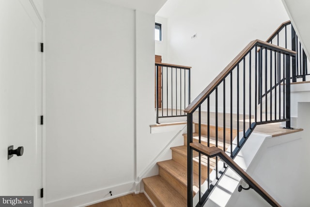 stairway with hardwood / wood-style flooring and a high ceiling