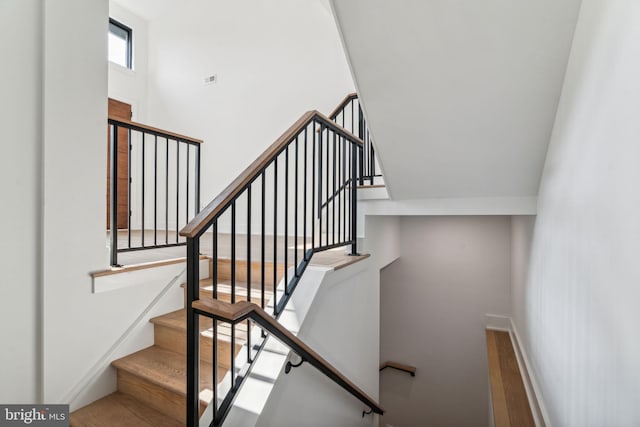 stairway with a high ceiling and hardwood / wood-style floors