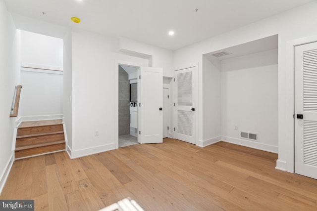 unfurnished bedroom featuring multiple closets and light wood-type flooring