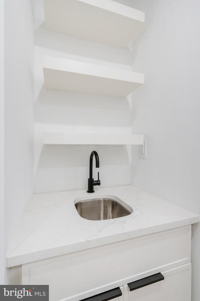 interior details featuring sink and light stone countertops