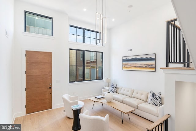 living room featuring light wood-type flooring and a towering ceiling