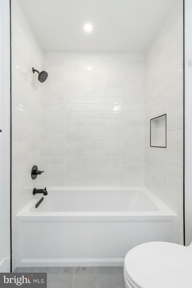 bathroom featuring tiled shower / bath combo, toilet, and tile patterned flooring