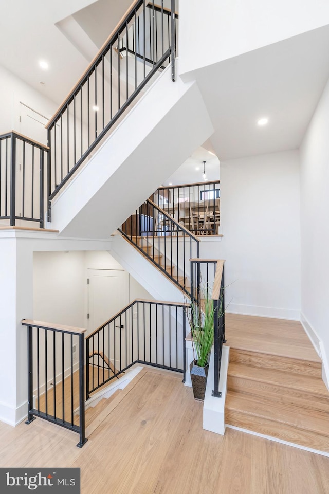 staircase featuring wood-type flooring and a towering ceiling