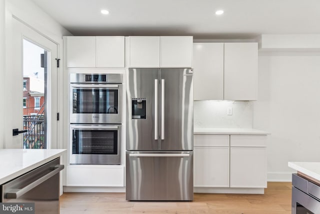 kitchen with white cabinetry, stainless steel appliances, and light wood-type flooring