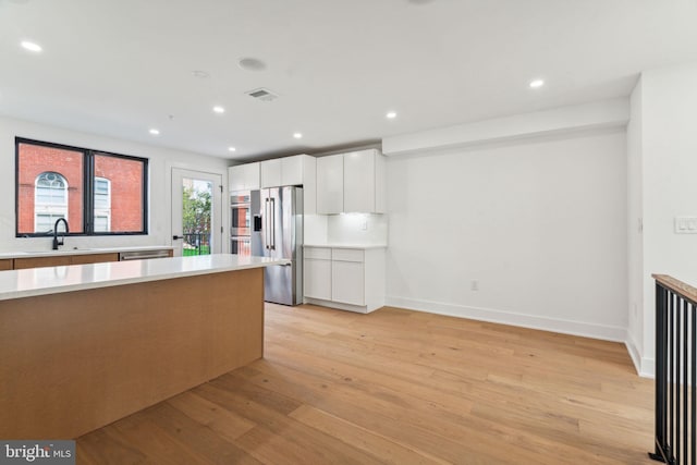 kitchen featuring sink, white cabinetry, light wood-type flooring, and stainless steel appliances